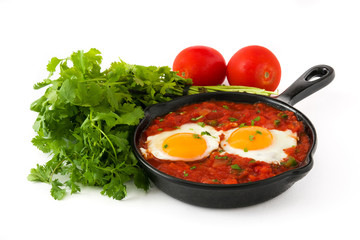 Mexican breakfast: Huevos rancheros in iron frying pan isolated on white background
