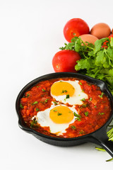Mexican breakfast: Huevos rancheros in iron frying pan isolated on white background
