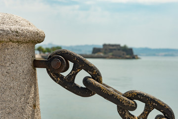 Strong metal weathered chain link barrier with a shallow depth of field and an unfocused fort in...