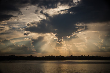 Beautiful sunset over the ocean with sun rays coming from behind the clouds