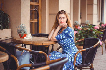 A girl in the American vintage style travels through Europe, sits in a cafe and has a good time
