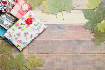 gifts and autumn leaves on wooden table