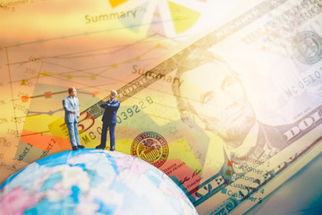 Miniature people on the globe world map with  graph and dollars banknotes  for finance and business concept