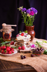 Obraz na płótnie Canvas Delicious pancakes with berries and cream on the authentic wooden stand. Summer food still life concept.