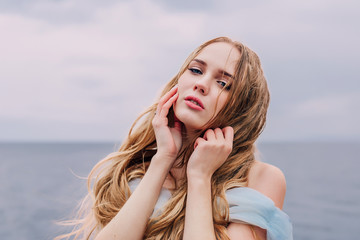 Beautiful girl with long blond wavy hair . Face close-up with raindrops