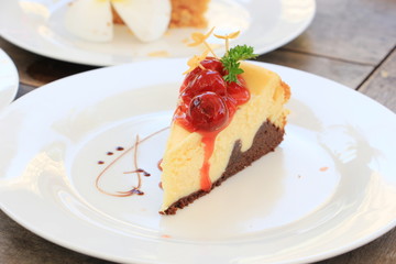 Slice of cheesecake with cherry sauce and ixora flower on white plate