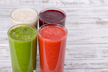 Fresh avocado, strawberry, blueberry and banana drinks on wooden table, assorted protein cocktails with fresh fruits.