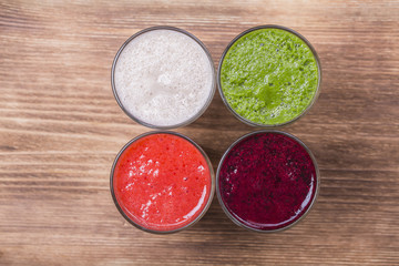 Fresh avocado, strawberry, blueberry and banana drinks on wooden table, assorted protein cocktails with fresh fruits.