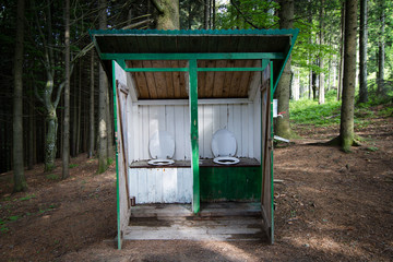 outdoor toilet with two seats in a forest
