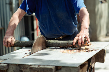Man making firewood with buzz saw in the yard of a private house.
