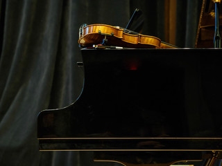 Violin on the grand piano in a concert hall