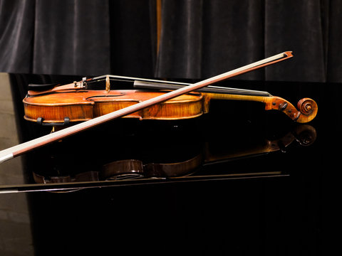 Violin on the grand piano in a concert hall