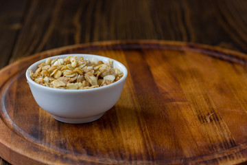 Granola or muesli in white ceramic bowl over wooden table.