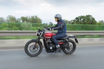 Fototapeta na wymiar Man in blue jeans, grey helmet riding fast red motorcycle