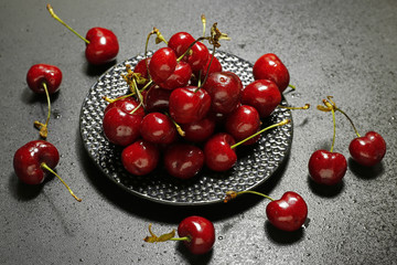 fresh cherries on a black plate with water drops