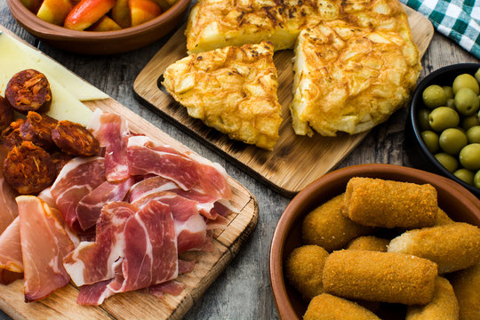 Traditional spanish tapas. Croquettes, olives, omelette, ham and patatas bravas on wooden table
