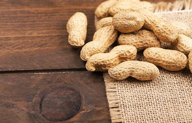 From above peanuts on canvas bag. Wooden background. Copy space.