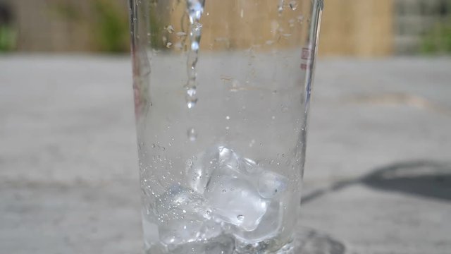 water Splashing into glass of ice refreshing slow motion 