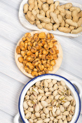 Peanuts, pistachios and toasted corn on wooden background. Vetical studio shot.