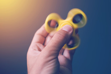 Yellow fidget spinner in male hand