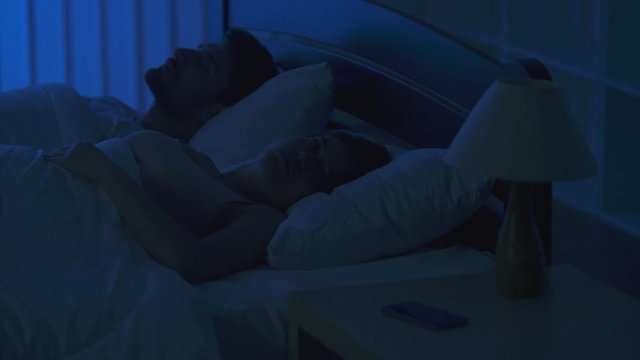 The woman lay on the bed and phone near the man. night time