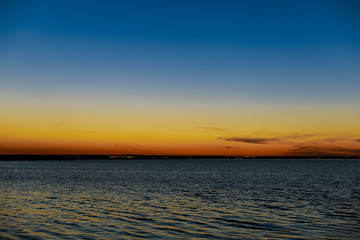 Sunset over the lake with the lights of a small town in the distance
