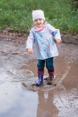 Little girl jumping in the puddle