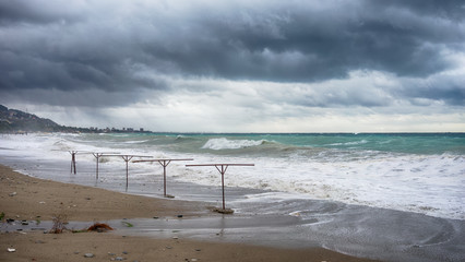 The landscape of the stormy sea under the dark clouds and the sandy beach