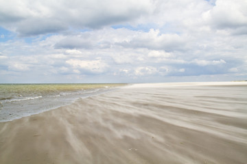 Sand blowing over the beach towards the sea of a stormy day