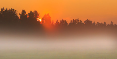 Fototapeta na wymiar Foggy sunset at countryside in Finland