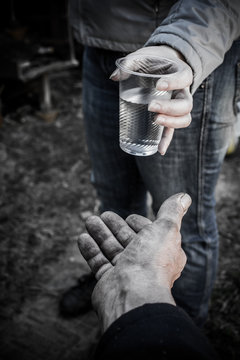 Woman giving a glass of water an adult male. From hand to hand.
