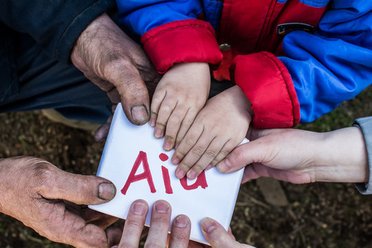 Several pairs of hands holding a box. The inscription on the box "Aid".
