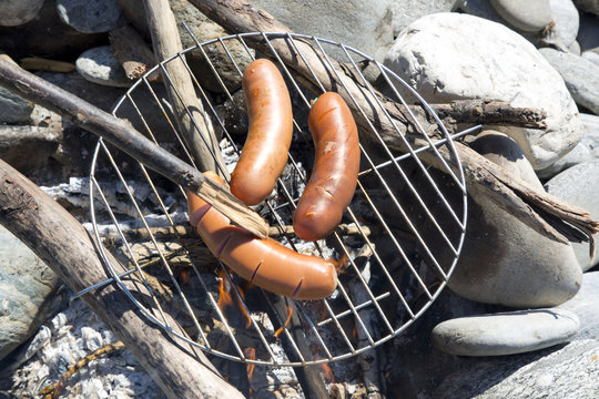 Broiling knacker sausages on open fireplace