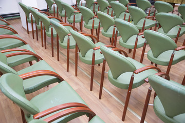 Group of empty the same chairs with modern backrest and green upholstery in rows at unknown...