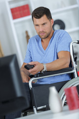 Fototapeta na wymiar handsome handicapped man watching television in living room