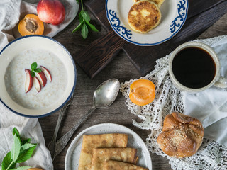 Breakfast table of oatmeal, pancakes, Cottage cheese pancakes , coffee and fruit. Top view. Rustic style