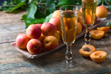 Juicy apricots with leaves and glass of sweet wine .