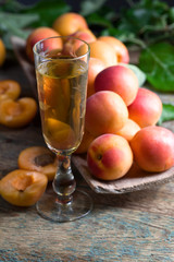 Juicy apricots with leaves and glass of sweet wine .