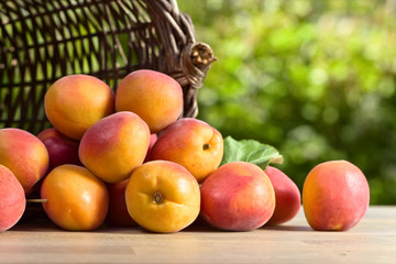 Fototapeta na wymiar Basket with fresh juicy apricots on wooden table .