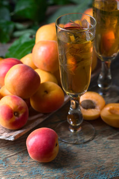 Juicy apricots with leaves and glass of sweet wine .