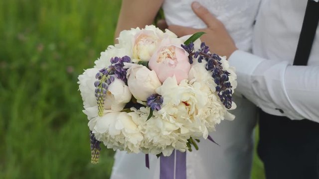 Beautiful bouquet of different colors in the hands of the bride in a white dress. Happy married couple with a wedding flowers.