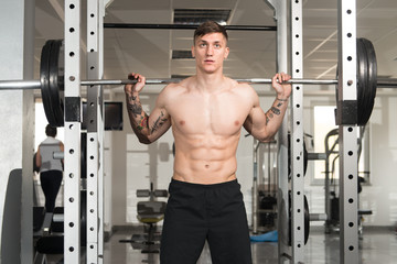 Fototapeta na wymiar Fitness Man Using Barbell Exercising Legs Inside Gym