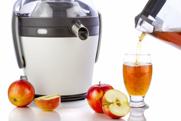 Electric juicer making apple juice on white background. Pouring healthy juice in glass.