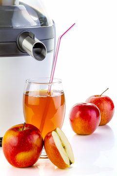 Electric juicer making apple juice on white background. Pouring healthy juice in glass.