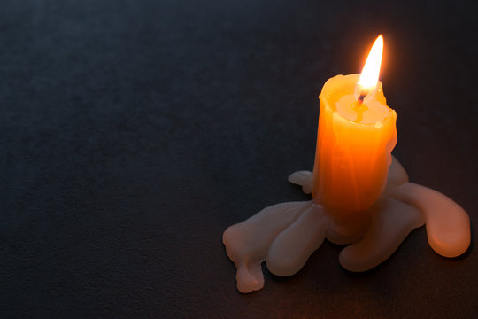 Burning candle and wax on a black background with space for text