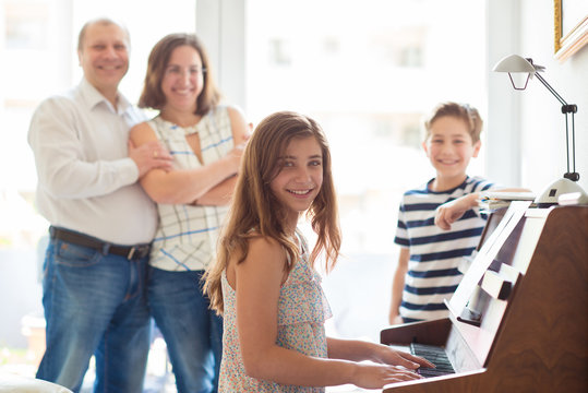 Happy young family listening how cildren plays piano music