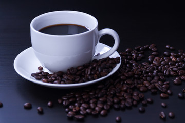 Hot coffee in the white cup and roasted on dark background
