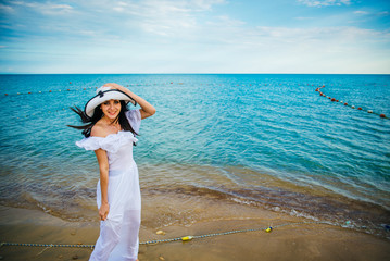 Fototapeta na wymiar Woman in hat and white dress on the background of the sea