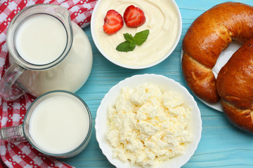 Milk background. Glass jug pitcher of fresh milk with glass, sour cream, cottage cheese and croissant on blue wooden background. Top view with copy space.
