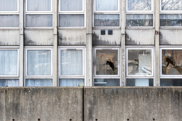 Vandalism, broken windows of a dilapidated council flat housing block